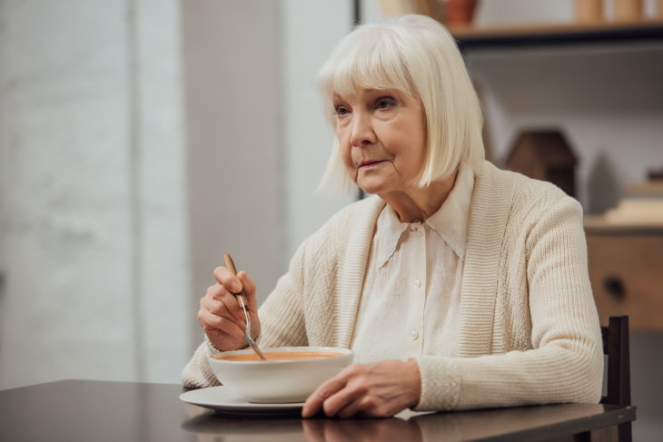 Foods That Increase the Risk of Alzheimer’s and Dementia sad woman eating soup