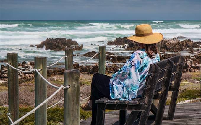 A woman sitting on a bench in front of the beach