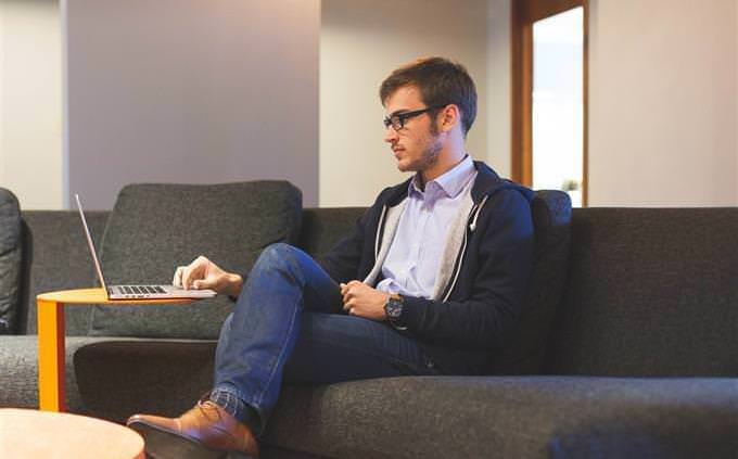 A person sitting on a sofa working on a laptop