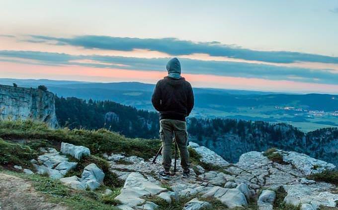 A man standing on a mountain looking at the landscape in front of him