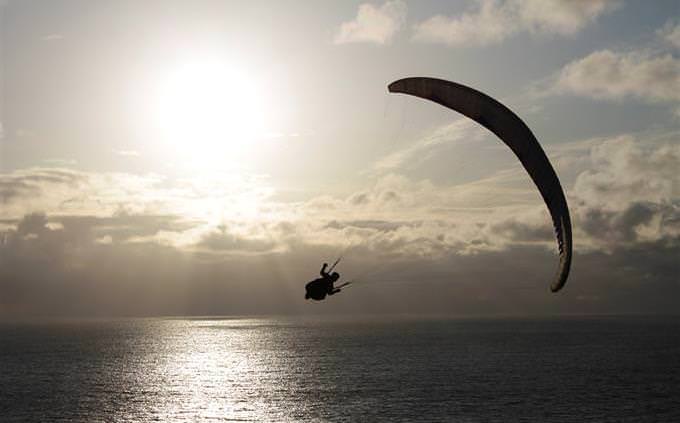 A man gliding in the sky with a parachute