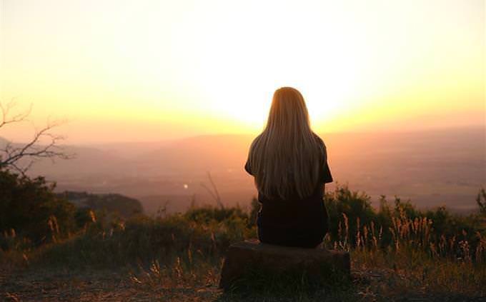 A woman sitting outdoors opposite the sunset