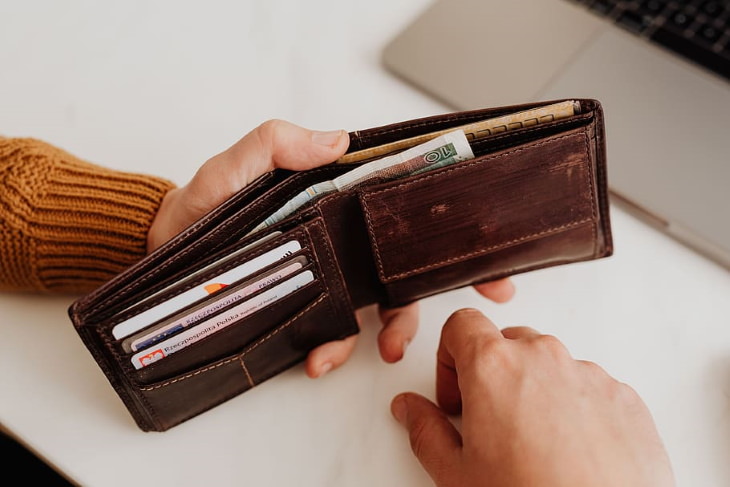 How to Go Grocery Shopping Less Often hand holding an open wallet