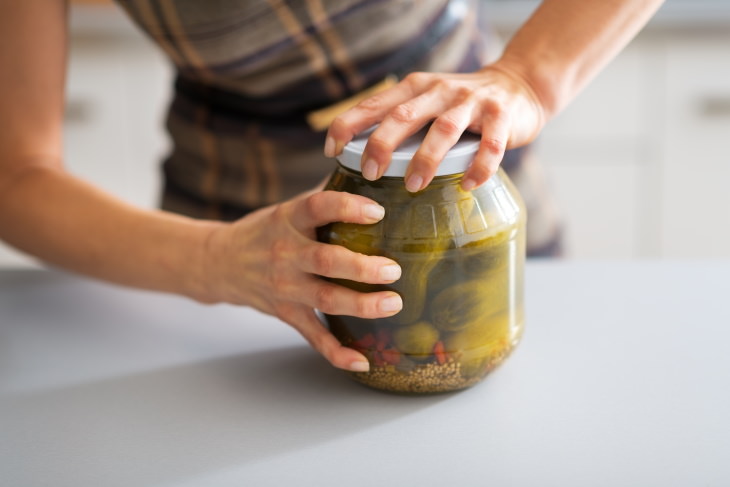 How to Open a Stuck Jar Lid woman opening a jar of pickles