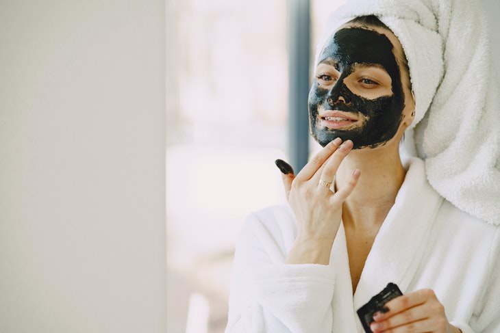oily skin causes and tips woman applying a face mask
