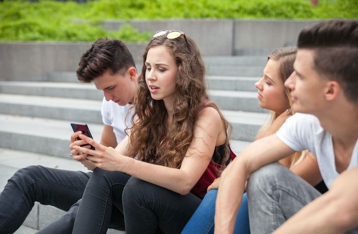 Body Language Habits That Make You Seem Disingenuous, woman looking at phone