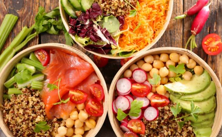 3 wooden salad bowls full of salad