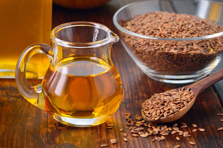 Flaxseed Oil bottle near a bowl of flaxseeds