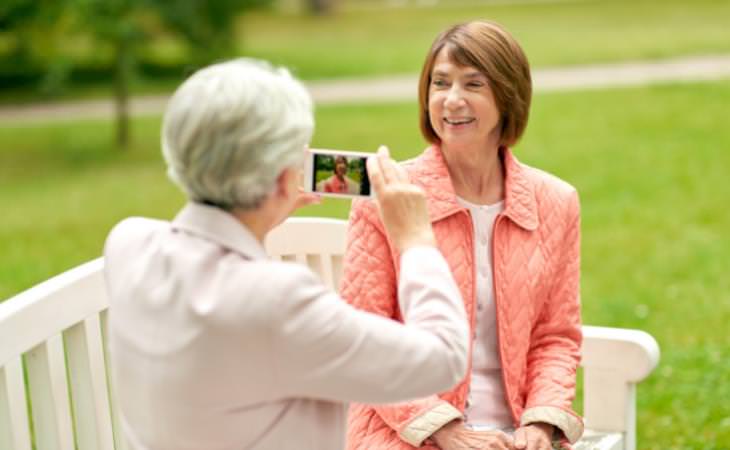 two women taking a picture sitting on a bench