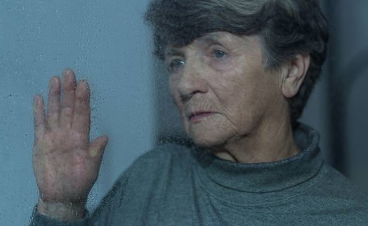 elderly woman looking out sad rainy window 
