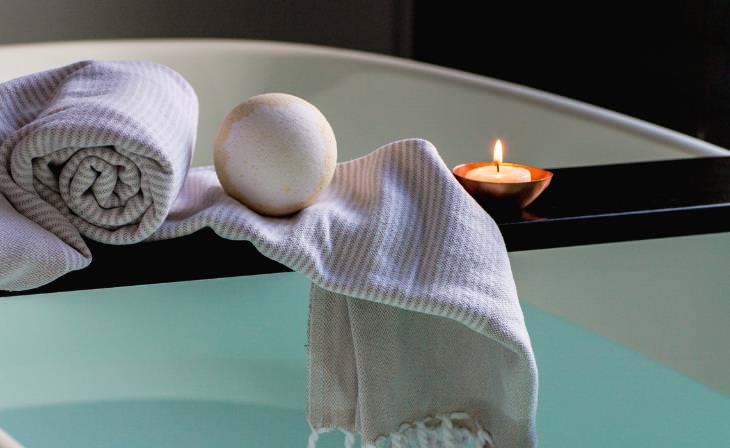 bath tray with lit candle, towel and a bath bomb