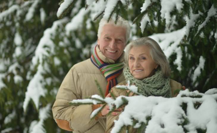 senior couple out near a snowy pine