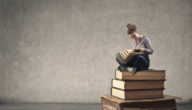 woman reading book sitting on gigantic books 