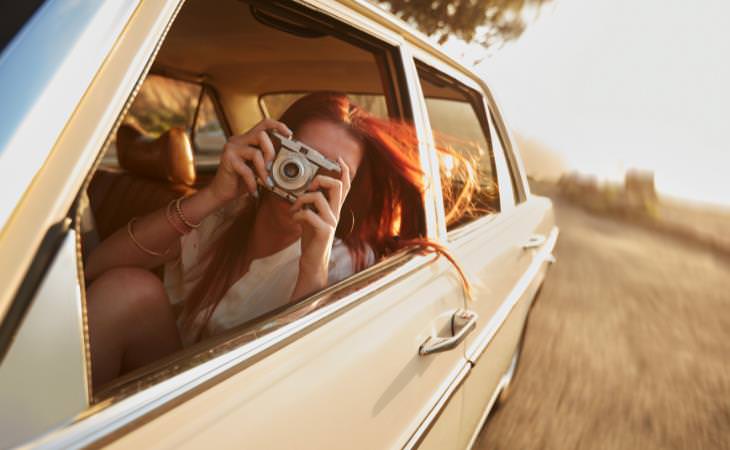 woman taking a photograph in a car