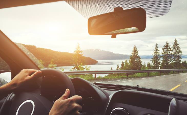 hands on the wheel driving near a lake