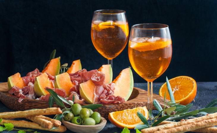 Aperitif: two cocktails with finger foods and cut fruits 