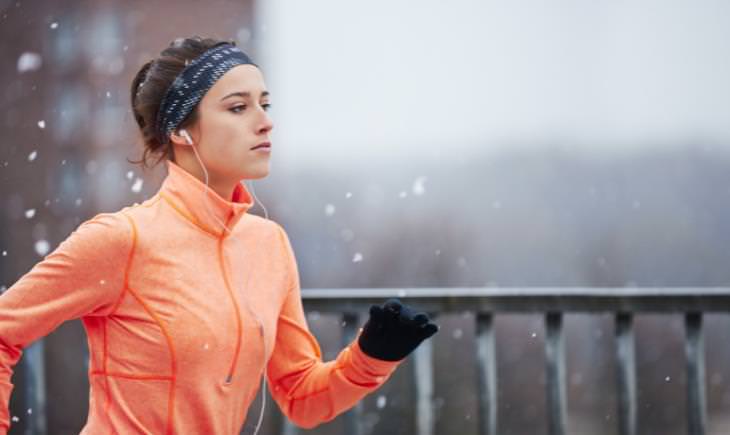 woman with earphones jogging in the snow