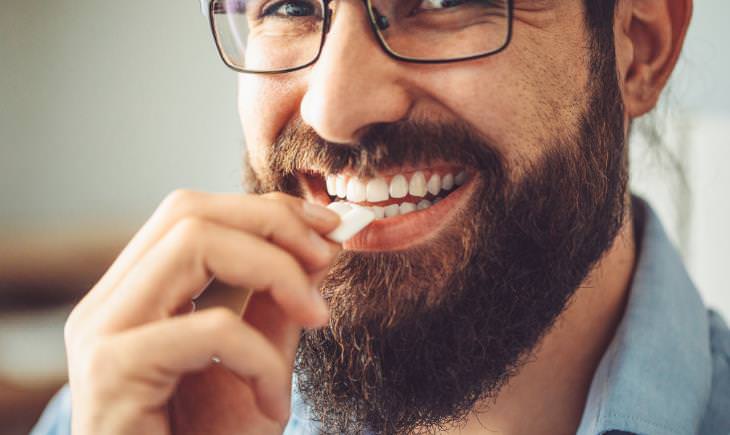 man with glasses smiling and chewing gum