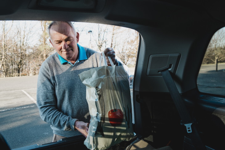 Stiff Neck man putting bag into car