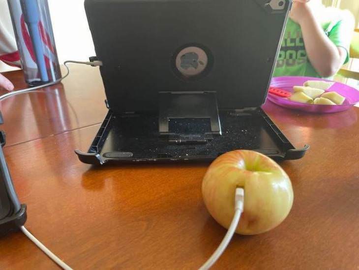 18 Photos of Kids in Hilariously Weird Situations, charging tablet with an apple