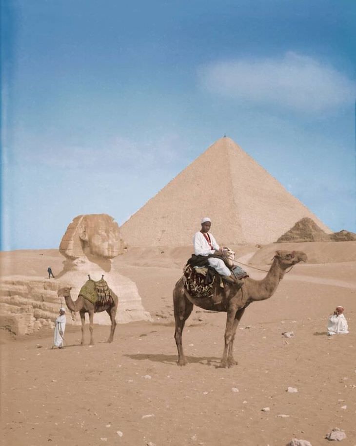 Rare and Beautifully Colorized Historical Photo Two locals stand in front of a man posing on top of the Sphynx, Giza, c. 1900