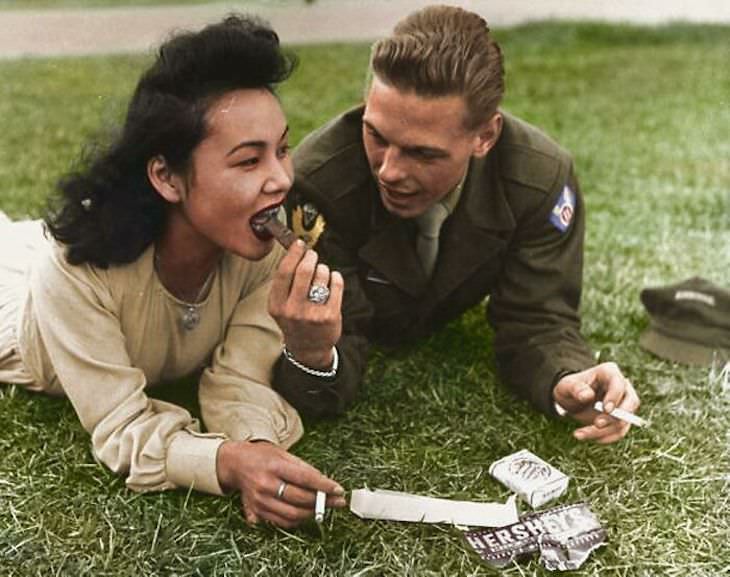 Rare and Beautifully Colorized Historical Photo US soldier from the 11th Airborne Division shares a bit of chocolate with a local girl, 1946, Japan