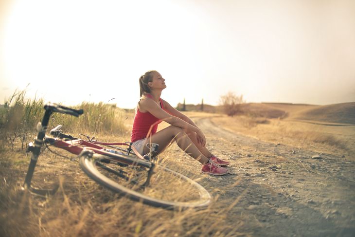 Exercising in the Summer Heat woman in nature sitting next to a bike