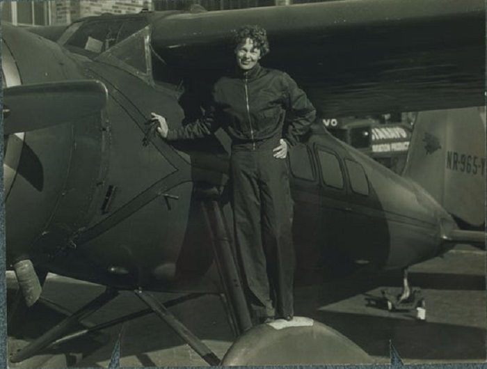 Amelia Earhart standing on her airplane, 1934