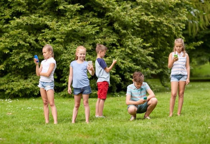 Kids using smartphones on the lawn 