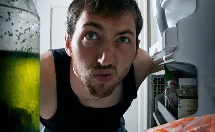 man peeking into the fridge 