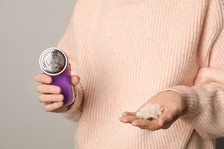 Pilling on Fabrics woman in a sweater with pill remover and a pile of lint