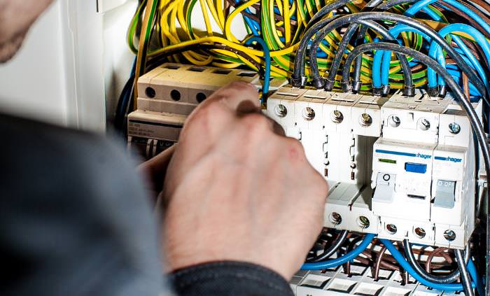 hand fixing wires on an electricity board