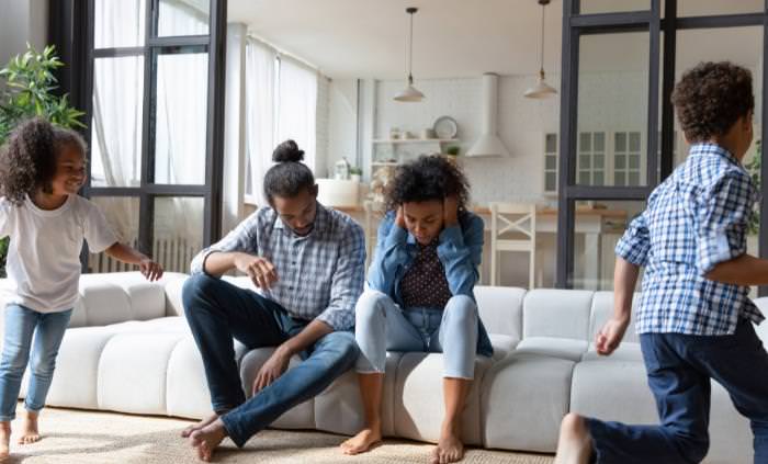 two children running around, parents upset on the couch