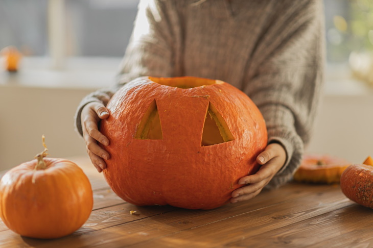 How to Make Carved Pumpkins Last Longer woman carving a pumpkin