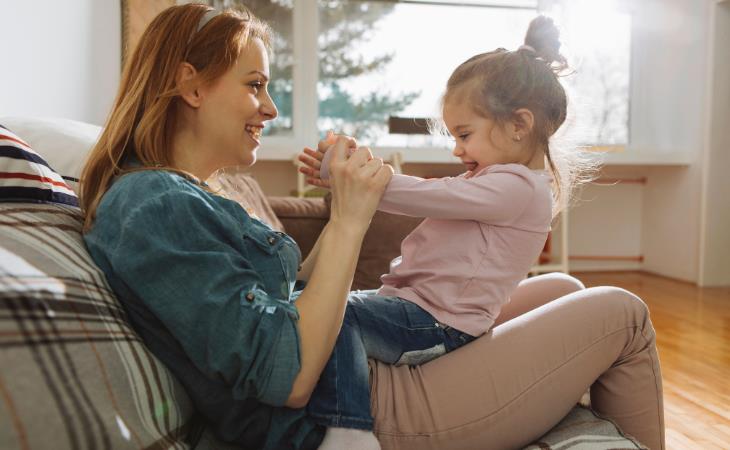 mother playing with daughter in her lap 