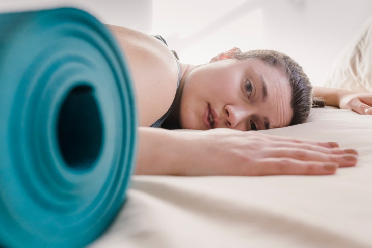 Constipation Myths tired woman next to yoga mat
