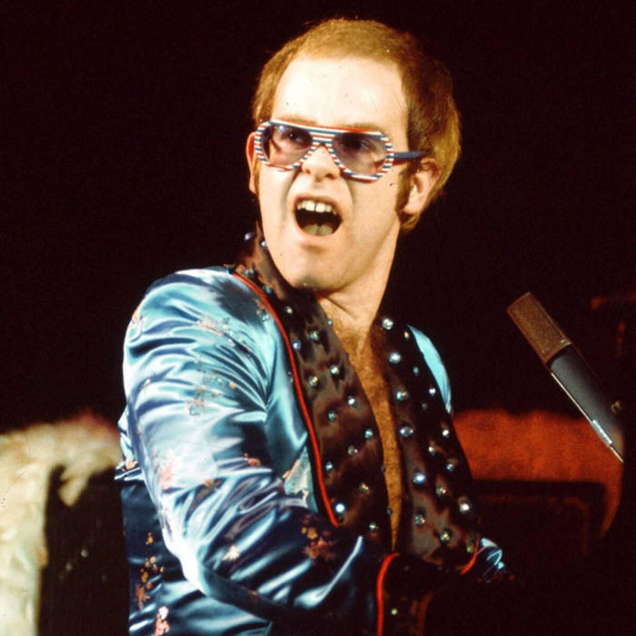 Elton in blue jacket and colorful glasses