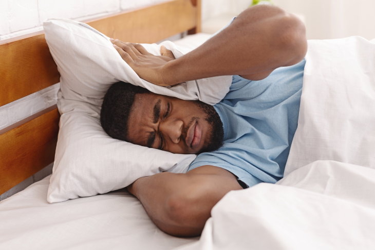 Exploding Head Syndrome man trying to sleep in noisy room