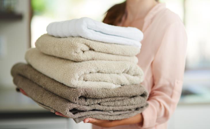 Laundry stripping woman holding clean folded towels