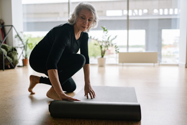 Arthritis Winter Flareups woman unrolling yoga mat