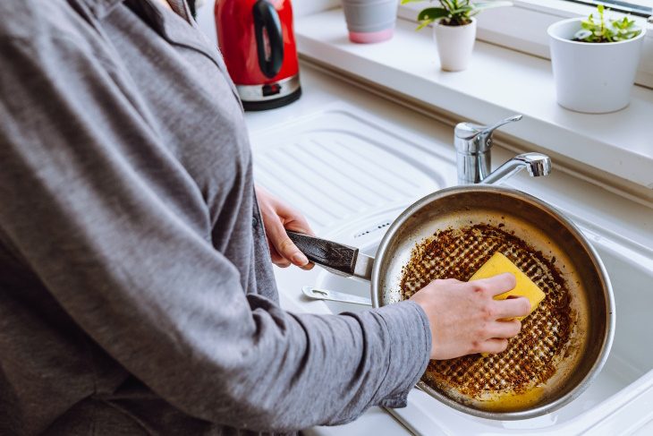 How to Remove Burnt Frying Pans woman scrubbing a pan