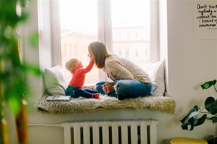 woman and toddler sitting in the window