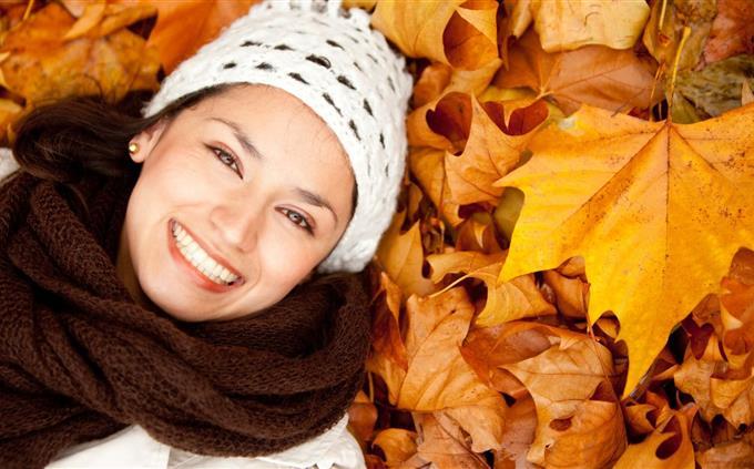 Find the differences in autumn: a smiling woman lying on fallen leaves