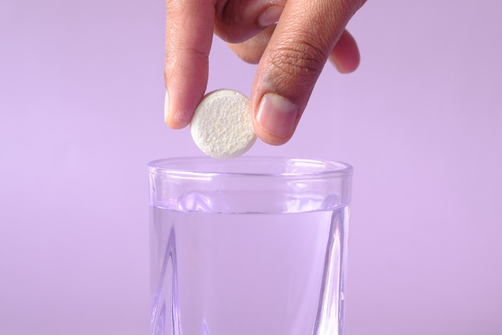 Dropping a table of Alka Seltzer in a glass of water