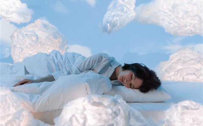 What your sleeping habits reveal about your future: A woman sleeps peacefully surrounded by clouds