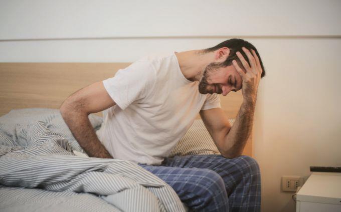 Are you worn out or stressed: A man sits on a bed holding his head