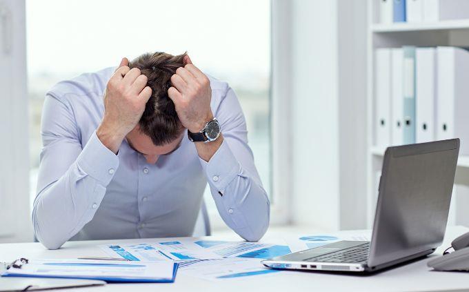 Are you worn out or stressed: a man in front of a computer holding his head