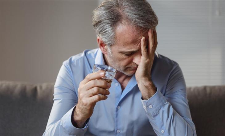 The connection between chronic pain and alcohol consumption: A person holding a glass of alcohol