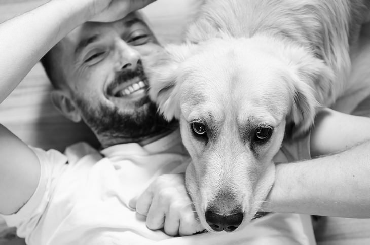 Signs your dog loves you: Dog resting his head on his smiling owner's lap