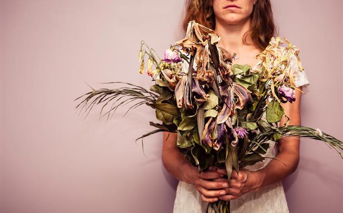 A test of flowers and romance: a woman holds a wilted bouquet